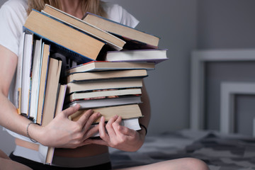 happy beautiful slim girl holds a lot of different books in her hands. Homeschooling. Studying in...