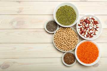 .Veggie protein source. Legumes lentils, chickpea, mung bean, bean, flax seed, chia on bowls on white background, copy space, top view.