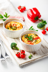 Vegetable frittata with broccoli, red bell pepper and red onion in cast iron skillet.