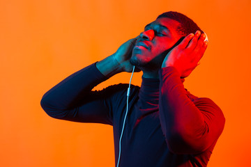 Neon portrait of handsome african american man in headphones. Listening to music.