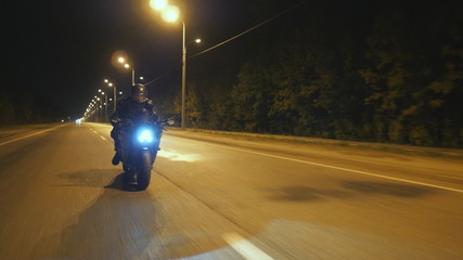 Young man in helmet riding fast on modern sport motorbike at evening city street. Motorcyclist...