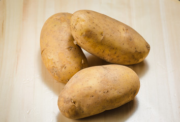 three potatoes on a light wooden.