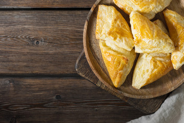 Puff buns in a wooden plate on a wooden Board on a brown wooden table. Confectionery. Rustic style. Top view with space for text