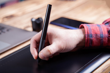 The workplace of the designer, men's hands work on a graphics tablet.