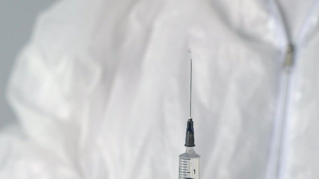 Hands medical nurse preparing syringe injection with needle. Male doctor in medical gloves removing air bubbles from syringe. Antiviral vaccine against coronavirus