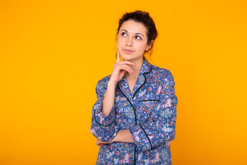 Excited young woman in blue home wear, widely smiling having fun. Isolated on yellow background. Copy space.