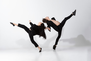 Young and graceful ballet dancers in minimal black style isolated on white studio background. Art, motion, action, flexibility, inspiration concept. Flexible caucasian ballet dancers, weightless jumps