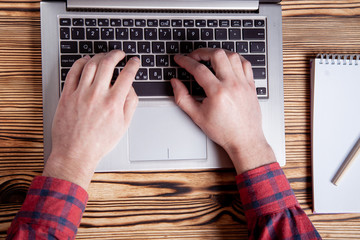 Workplace, male hands are typing on a laptop.