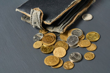 Old battered wallet and lot of coins on concrete desk. Concept of social payments and donations,...