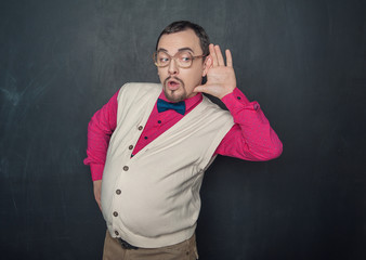 Funny thick teacher or business man with hand near his ear on blackboard