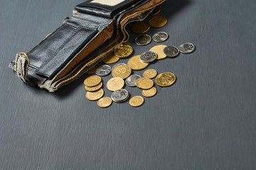 Old battered wallet and lot of coins on concrete desk. Concept of social payments and donations,...