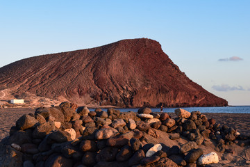Red volcanic rock mountain at the spanish beach of La Tejita, Tenerife, Canary Island. Next to the...