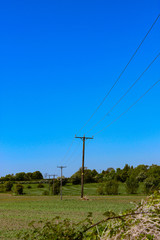Fototapeta na wymiar high voltage power lines in the countryside with a blue sky background 