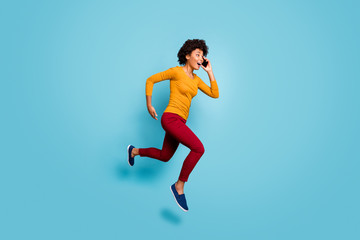 Fototapeta na wymiar Full length body size view of nice attractive cheerful motivated energetic wavy-haired girl jumping talking on cell running fast hurry rush isolated on bright vivid shine vibrant blue color background