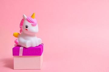 gifts, unicorn figurine and gift box for a party on a pink background