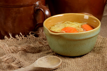 carrot broth in a small bowl next to wooden spoons on a rustic table