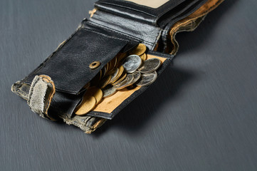 Old battered wallet and lot of coins on concrete desk. Concept of social payments and donations, poverty