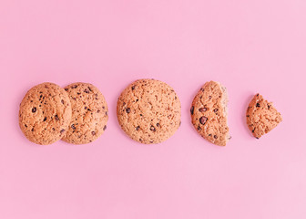 Oatmeal cookies Top view photo Whole and crushed into pieces oatmeal cookies are lying in a row on a pink background