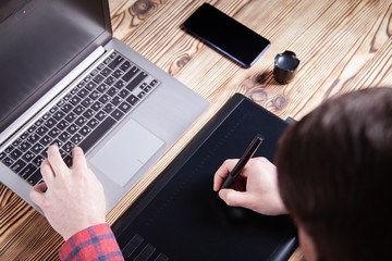 The workplace of the designer, men's hands work on a graphics tablet.