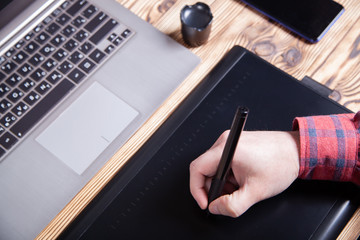 The workplace of the designer, men's hands work on a graphics tablet.