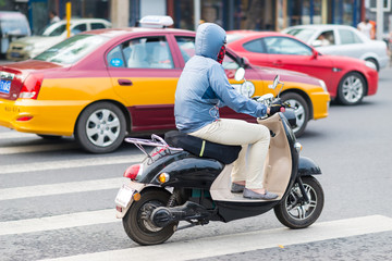 China, Peking, Vermummter Rollerfahrer im Straßenverkehr