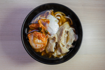 A bowl of udon with pork, egg, and kimchi.