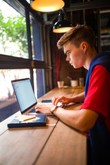 Male skilled publication specialist creating promotional article on pc laptop computer while relaxing in coffee shop interior. Hipster guy using applications on net-book gadget
