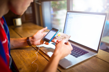 Business man online shopping store via mobile phone and using credit card for payment during freelance wok on laptop computer while relaxing in coffee shop