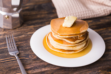 Small pancakes with maple syrup and butter on wooden table. Breakfast concept.