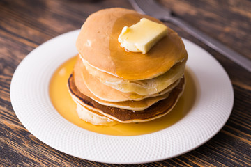 Golden pancakes with butter and warm maple syrup.