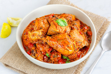 Spicy Indian Chicken Curry Served in a Bowl on the Burlap, Garnished with Lemon and Cilantro