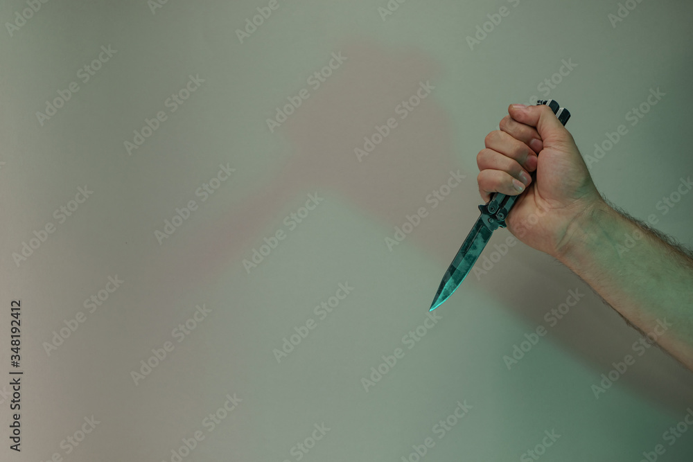 Poster Hand holding old butterfly knife in the color light. Beautiful old minimal in neon light. Minimalism retro style concept. Background pattern for design.