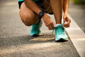 Close up on sporty woman  hands shoelace before jogging at park
