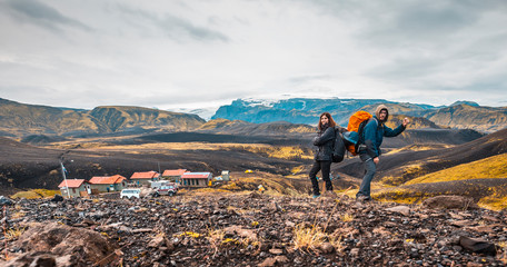 A couple with backpacks leaving the shelter of the 54 km trek from Landmannalaugar, Iceland