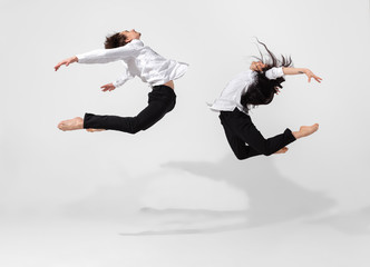 Young and graceful ballet dancers in minimal black style isolated on white studio background. Art,...
