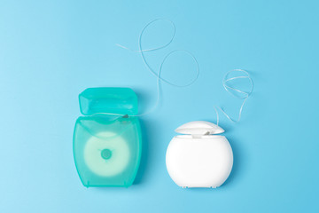 Dental floss containers on blue background. Daily oral hygiene, teeth care and health. Cleaning...