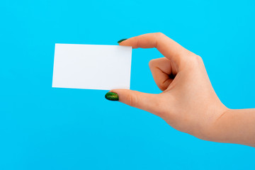 Obraz premium Woman hand holding blank card on blue background, close up.