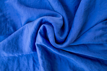 Blue indigo fabric, silk in iridescent smooth folds as modern background. The deep blue color of the noble light texture