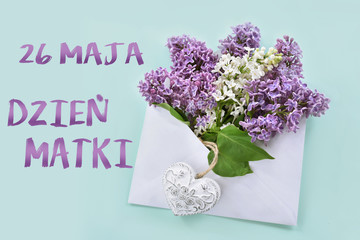 flat lay with white and purple lilac blossoms in envelope with inscription in Polish language translated as May 26th Mothers Day