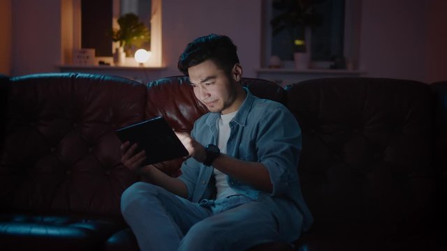 Emotional Handsome Asian men wins on game on tablet and enjoy it.