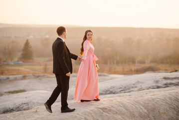 Happy wedding couple walk at beautiful landscape at sunset. Wedding concept.