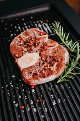 Raw beef steak with rosemary and peppers on dark ready to cook. Top view