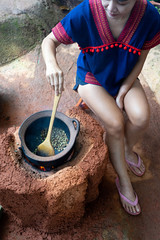 Asian woman roasting coffee bean in old clay pot