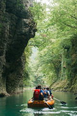 Fototapeta na wymiar Martvili Georgia June. A group of tourists floating in a rubber boat on the river Martvili canyon.