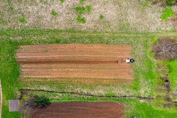 Tractor plows a small field in the village before planting vegetables. Aerial height view.