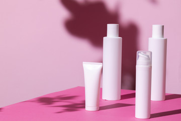 Skincare products containers on bright pink background close up