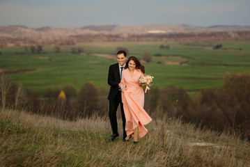 Happy bride and groom on their wedding day. Groom and Bride walking on a hilly area with a beautiful view.