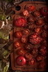 Red cherry tomatoes with lettuce on the Board. Tomatoes with spices and salt. Red and green. Cutting board