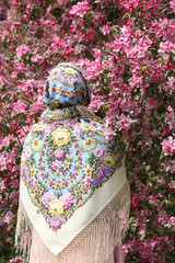 Russian fashionable girl in vintage Pavlovo Posad shawl. Pink flowers of blossoming apple-tree,...