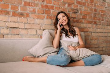 beautiful cheerful girl talking on smartphone during self isolation at home